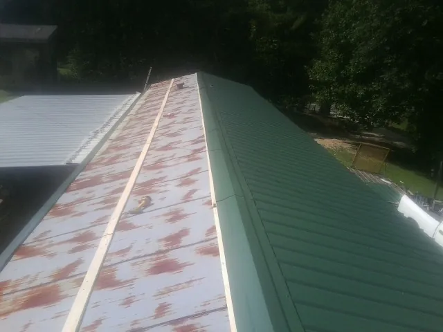Old rusted panels beside newly installed green metal roofing — Wind Damage Roof Repair by Roofing Brothers in Youngstown